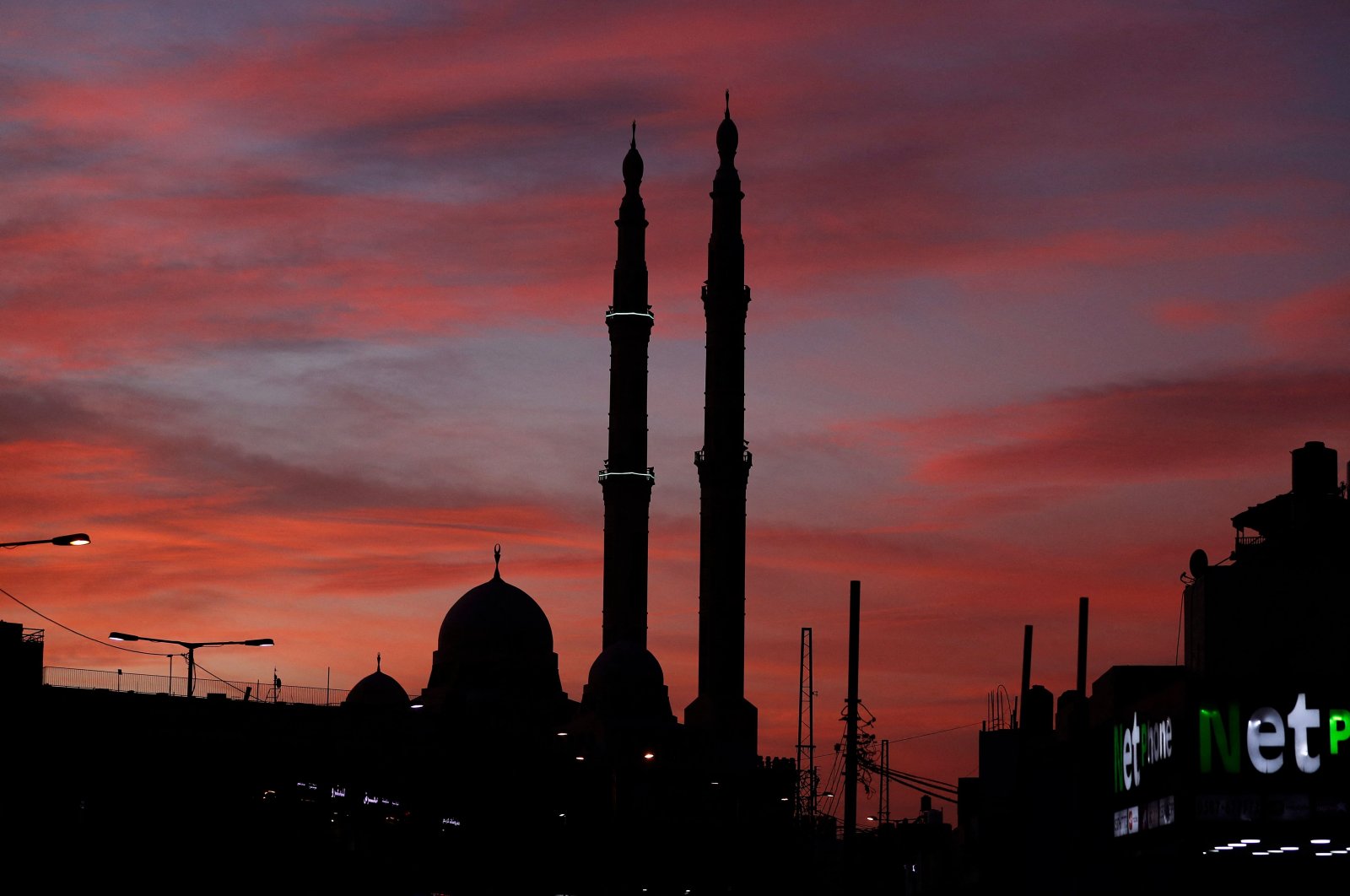 The sun sets behind the Sheikh Zayed Mosque in al-Azariya on the outskirts of Jerusalem on Nov. 30, 2021. (AFP Photo)