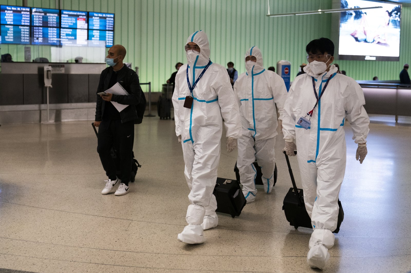 Air China flight crew members in hazmat suits walk through the arrivals area at Los Angeles International Airport in Los Angeles, California, U.S., Nov. 30, 2021. (AP Photo)