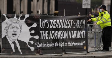 A police officer stands beside a protest banner at Parliament Square in London, Britain, Nov. 24, 2021. (AP Photo)
