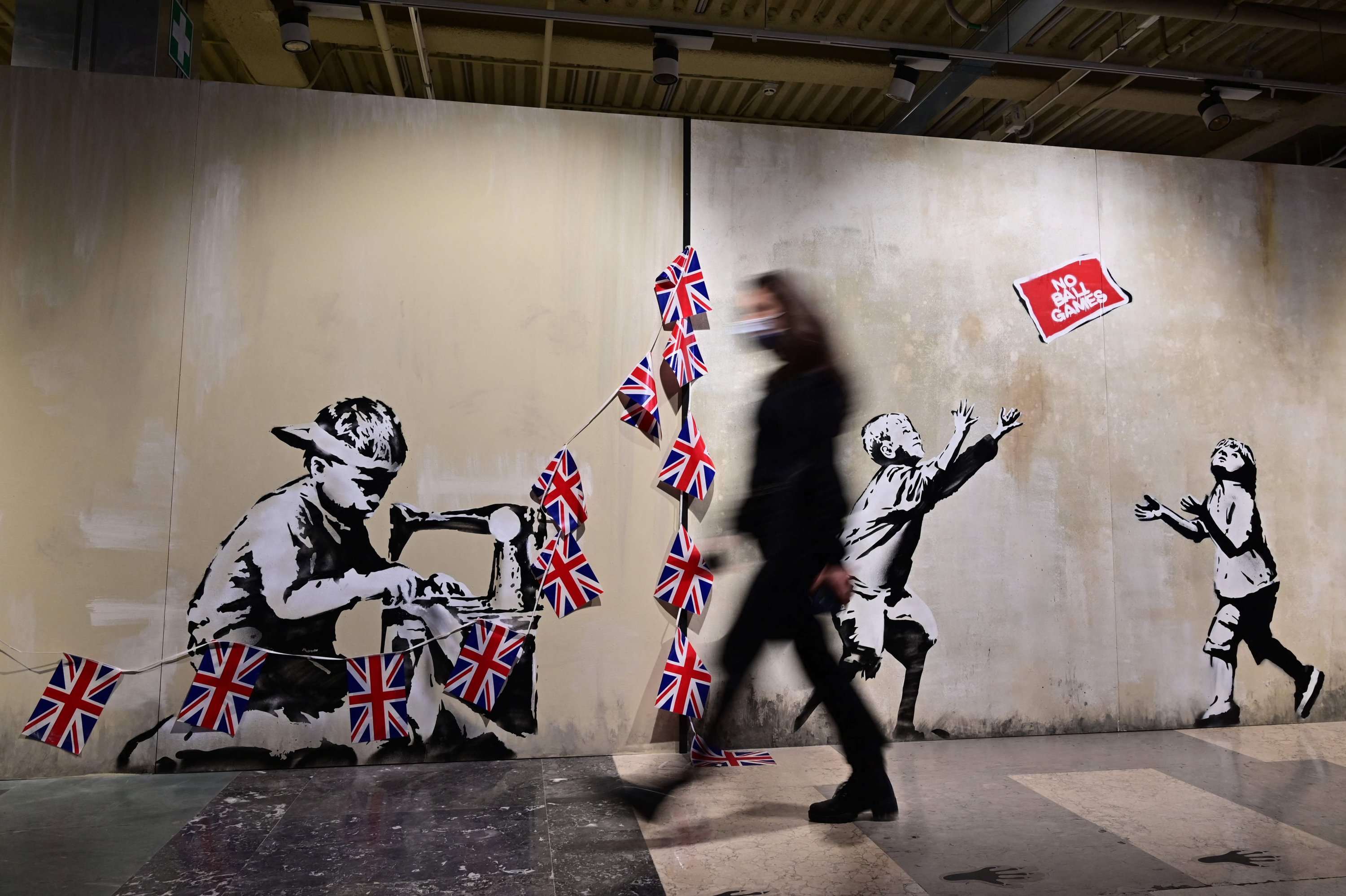 A visitor walks in front of a British street artist Banksy's murals 