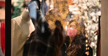 Shop attendants wearing protective face masks adjust the holiday display in the window of a women&#039;s clothing store in Glendale, California, Dec. 1, 2021. (AFP Photo)