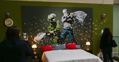 Visitors view British street artist Banksy's mural "Pillow Fight" during a preview of the exhibition “The Word of Banksy – The Immersive Experience" at the Milano Centrale main railway station in Milan on December 02, 2021. (AFP)