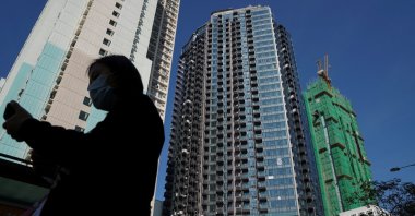 A pedestrian walks past a residential development in which Evergrande, according to sources, has transferred unsold units to its joint-venture partner VMS Group, Hong Kong, China, Nov. 27, 2021. (Reuters Photo)
