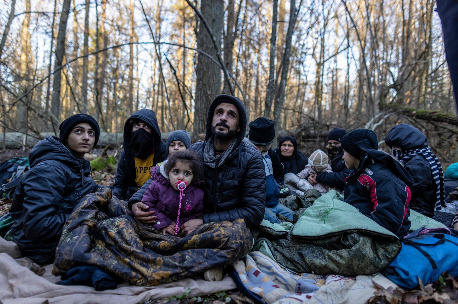 Members of a Kurdish family from Dohuk in Iraq are seen in a forest near the Polish-Belarus border while waiting for the border guard patrol, near Narewka, Poland, on Nov. 9, 2021. (AFP Photo)