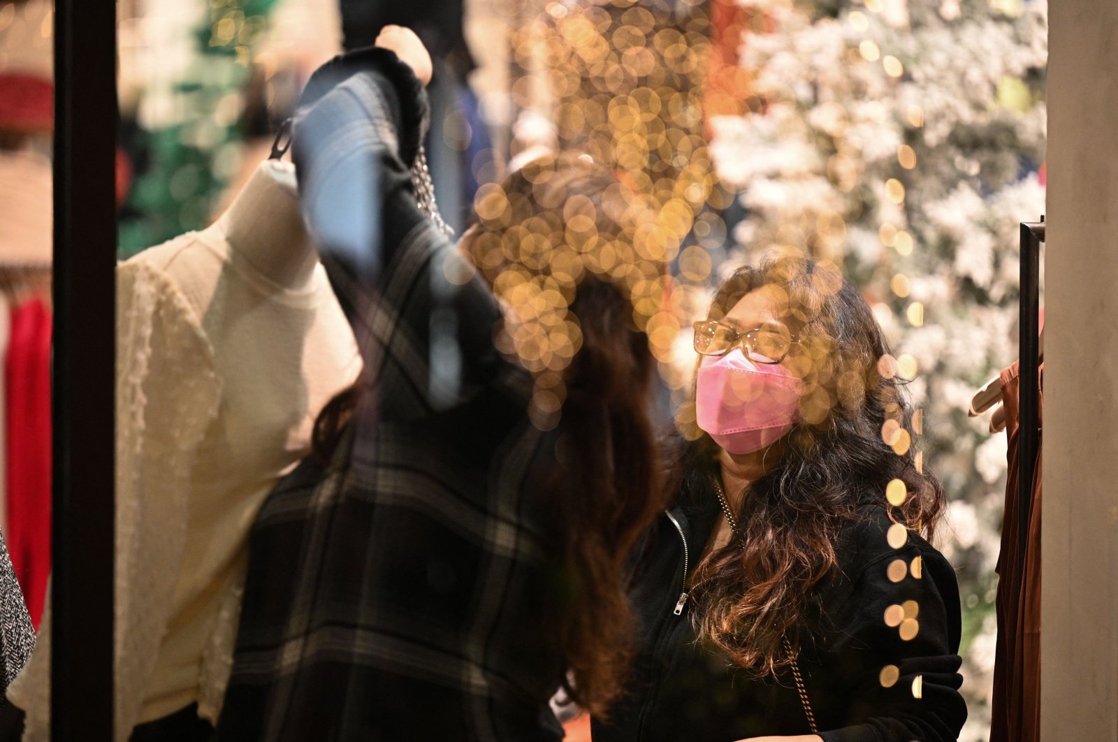 Shop attendants wearing protective face masks adjust the holiday display in the window of a women&#039;s clothing store in Glendale, California, Dec. 1, 2021. (AFP Photo)