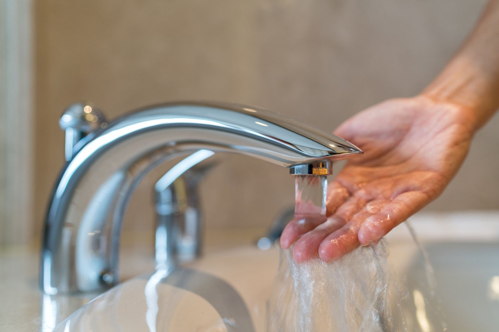 Woman taking a bath at home, checking the temperature and touching running water with her hand. (Shutterstock)