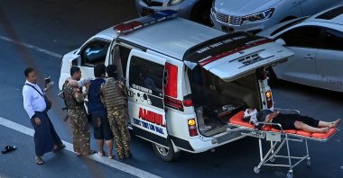 A journalist (3rd L), who was covering a protest against the military coup, receives medical attention as an injured protester lies on a stretcher beside an ambulance after a crackdown on the demonstration by security forces in Yangon, Myanmar, Dec. 5, 2021. (AFP Photo)