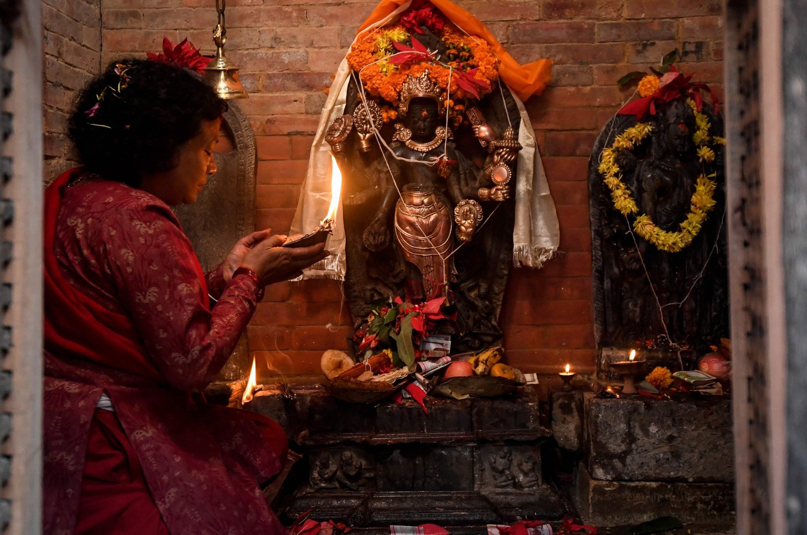 A devotee performs a prayer ritual before a centuries-old sculpture of a Hindu god that was reinstalled nearly 40 years after it was stolen, at its temple in Lalitpur, on the outskirts of Kathmandu, Nepal, Dec. 4, 2021. (AFP Photo)
