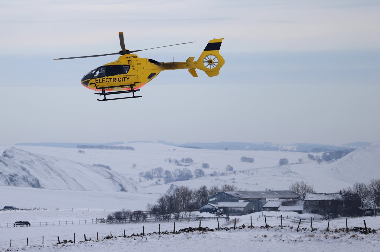 A Western Power Distribution maintenance helicopter flies over the snow-covered fields in Buxton after Storm Arwen, Buxton, Derbyshire, Britain, Nov. 29, 2021. (Reuters Photo)