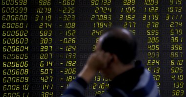 An investor sits in front of an electronic board displaying stock prices at a brokerage house in Beijing, China, Sept. 17, 2018. (AP Photo)