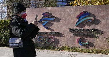 A visitor to the Shougang Park walks past the logos for the Beijing Winter Olympics and Paralympics in Beijing, China, Nov. 9, 2021. (AP Photos)