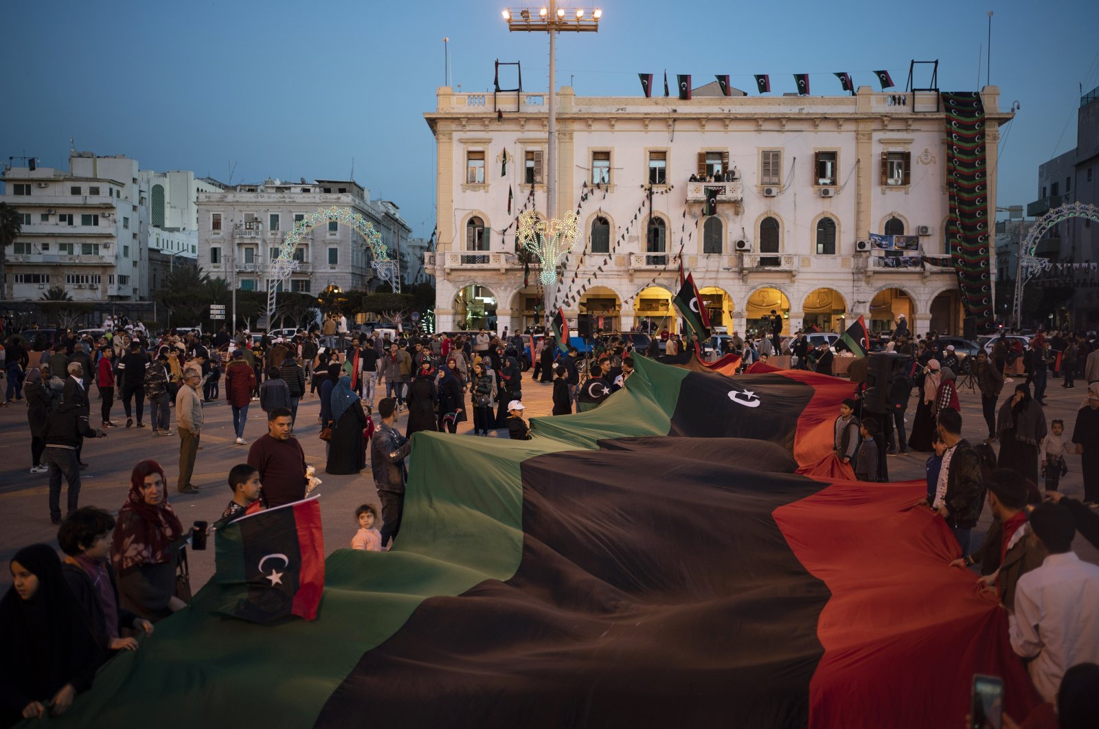 People carry a giant Libyan flag at Martyr Square during a march commemorating the anniversary of anti-Gadhafi protests in Tripoli, Libya, Feb. 25, 2020. (AP File Photo)