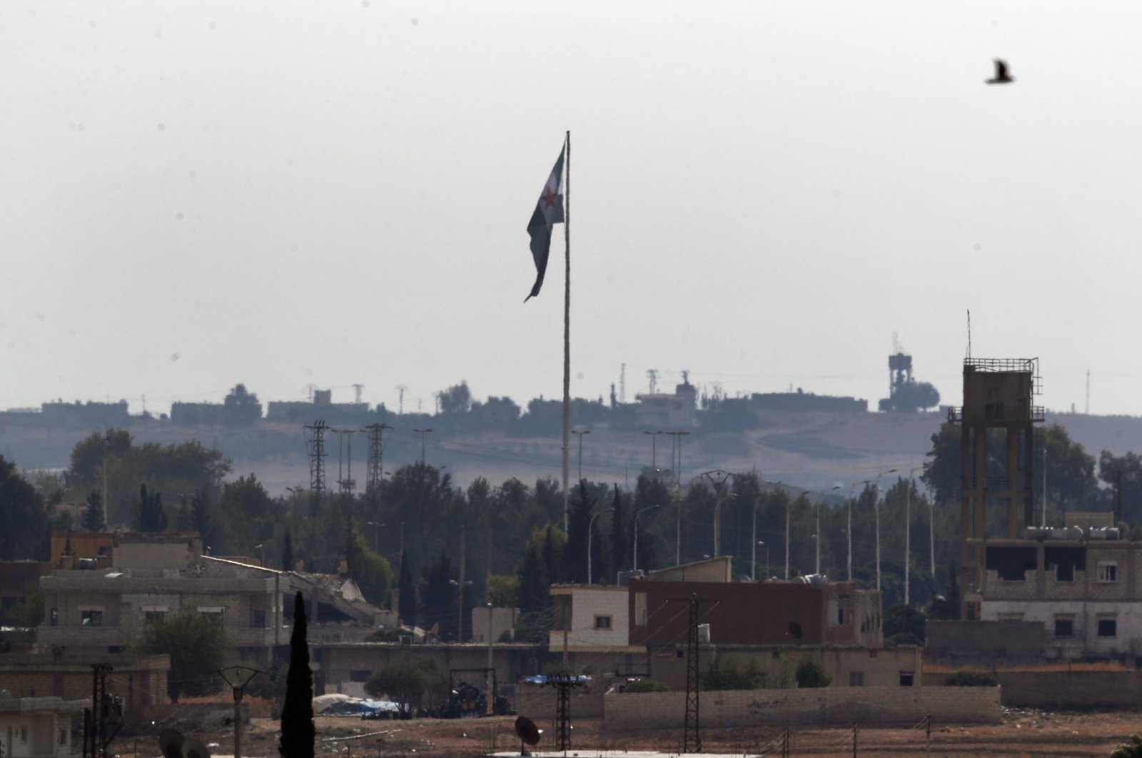 Photo from the Turkish side of the border between Turkey and Syria shows Syria&#039;s opposition flag flying on a pole in Tal Abyad, Syria, Oct. 22, 2019. (AP File Photo)