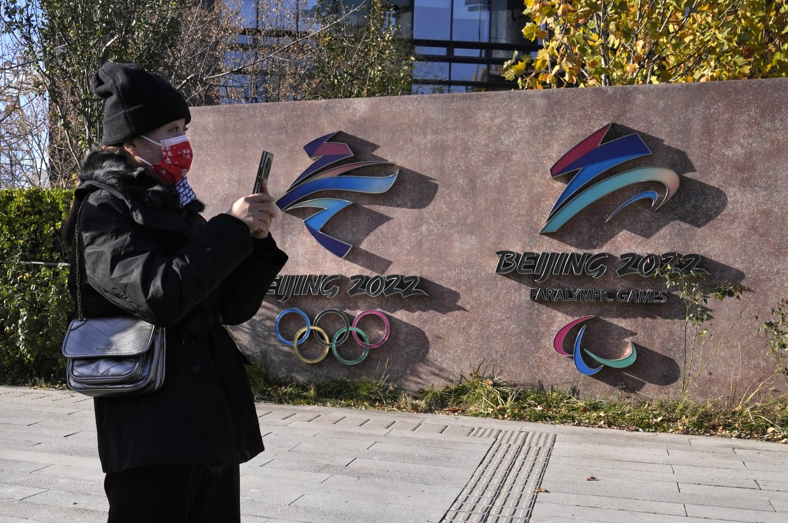 A visitor to the Shougang Park walks past the logos for the Beijing Winter Olympics and Paralympics in Beijing, China, Nov. 9, 2021. (AP Photos)