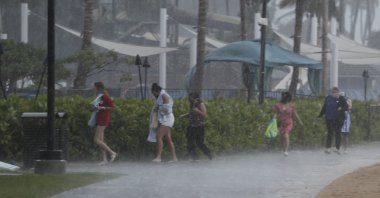 People scramble to get out of the heavy rain on Waikiki Beach, Honolulu, Hawaii, Dec. 6, 2021. (AP Photo)