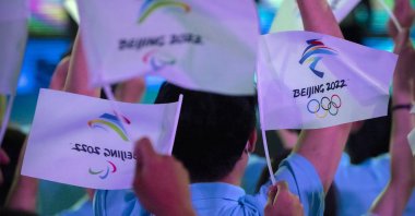 Participants wave flags with the logos of the 2022 Beijing Winter Olympics and Paralympics during an event in Beijing, China, Sept. 17, 2021. (AP Photo)