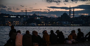 People sit near the shore of Bosporus during sunset in Istanbul, Turkey, Dec. 6, 2021. (AFP PHOTO)