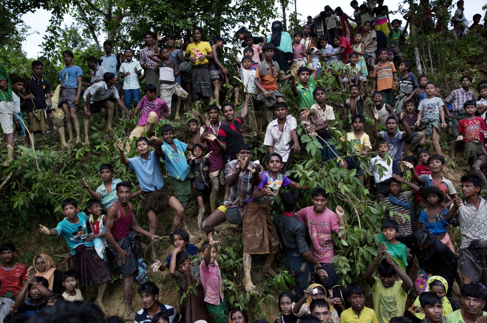 Rohingya Muslim refugees from Myanmar&#039;s Rakhine state stand on a slope and stretch their arms out to receive food being distributed near the Balukhali refugee camp in Cox&#039;s Bazar, Bangladesh, Sept. 20, 2017. (AP File Photo)