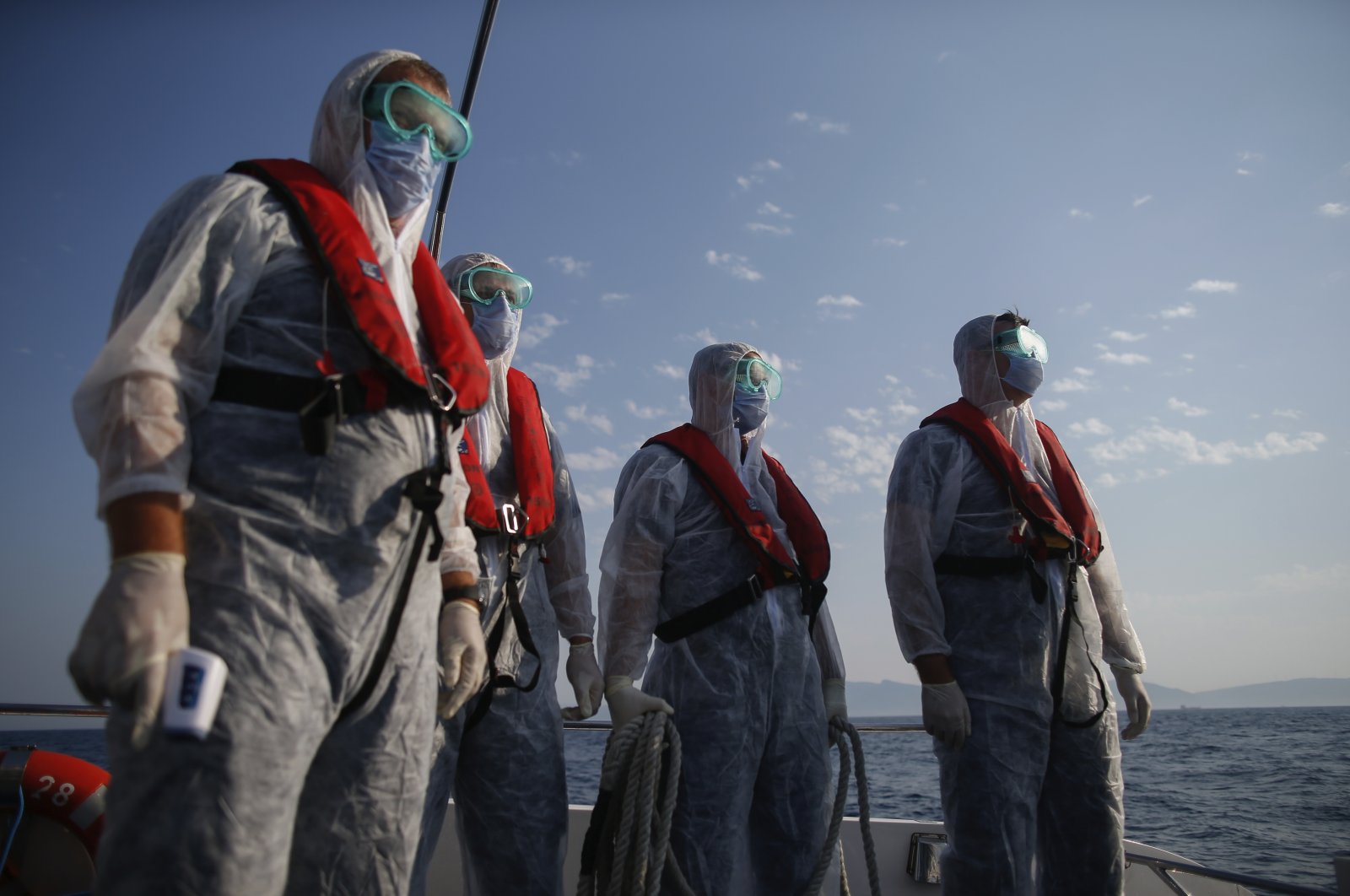 Turkish coast guard officers, wearing protective gear to help prevent the spread of the coronavirus, approach a life raft with migrants during a rescue operation in the Aegean Sea, between Turkey and Greece, Sept. 12, 2020. (AP File Photo)