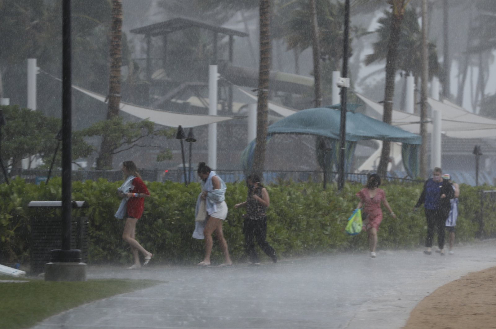 People scramble to get out of the heavy rain on Waikiki Beach, Honolulu, Hawaii, Dec. 6, 2021. (AP Photo)
