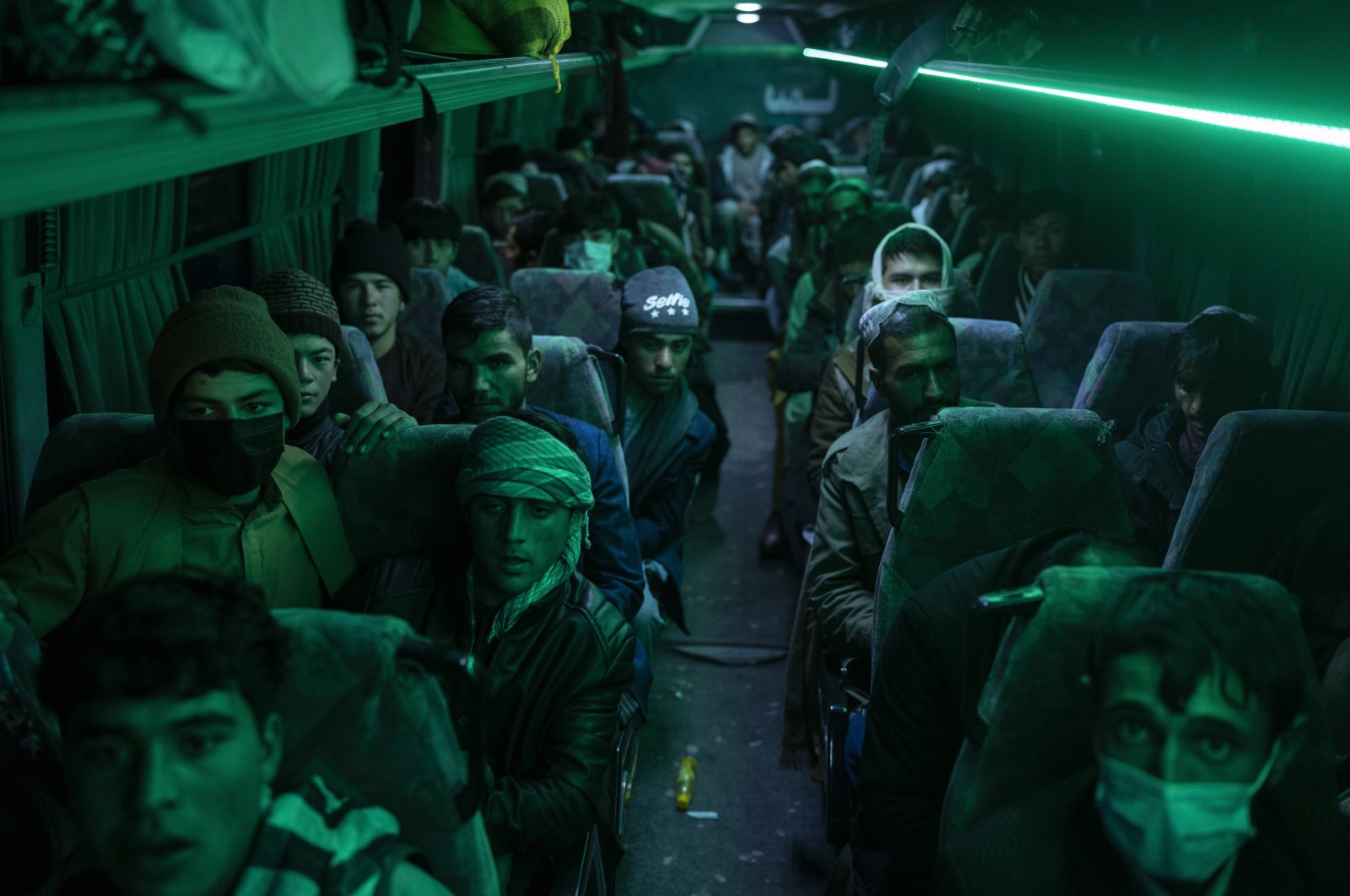 Afghan men sit in a bus for a 300-mile trip south to Nimrooz near the Iranian border, in Herat, Afghanistan, Nov. 22, 2021. (AP Photo)