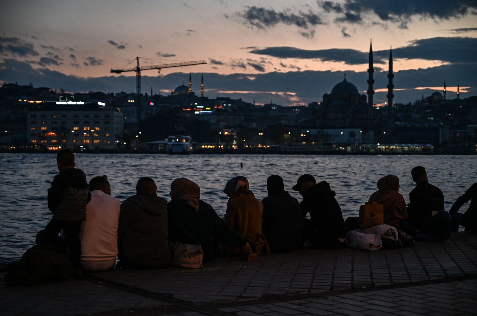 People sit near the shore of Bosporus during sunset in Istanbul, Turkey, Dec. 6, 2021. (AFP PHOTO)