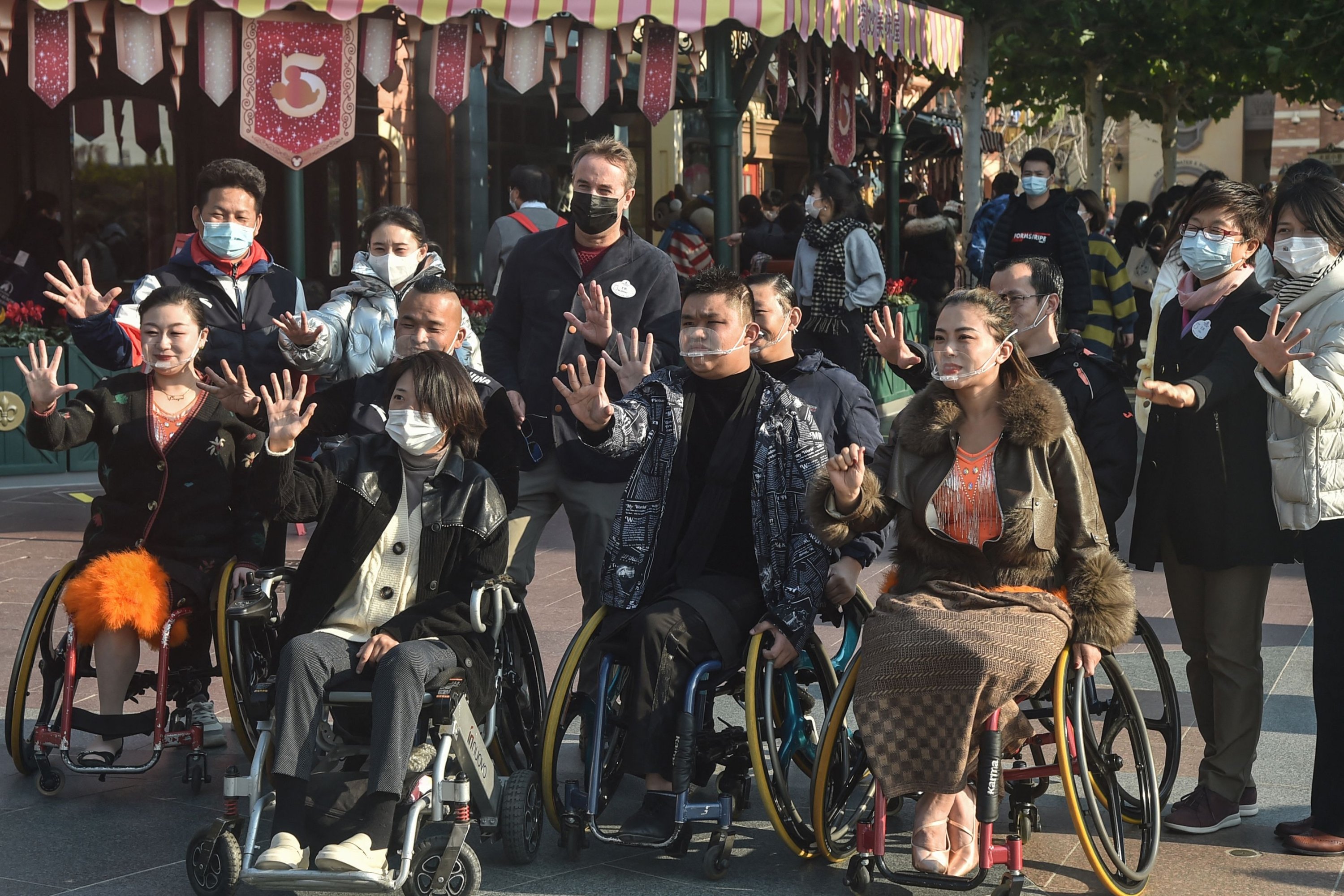 Wheelchair dancers from the Shanghai Oriental Pearl TV Tower Handicapped Art Troupe take photos with staff members of Shanghai Disneyland on the International Day of Persons with Disabilities, China, Dec. 3, 2021. (AFP)