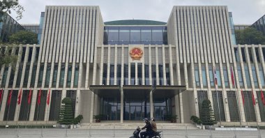 People ride a moped past the National Assembly building in Hanoi, Vietnam on Wednesday, Dec. 8, 2021. (AP Photo)