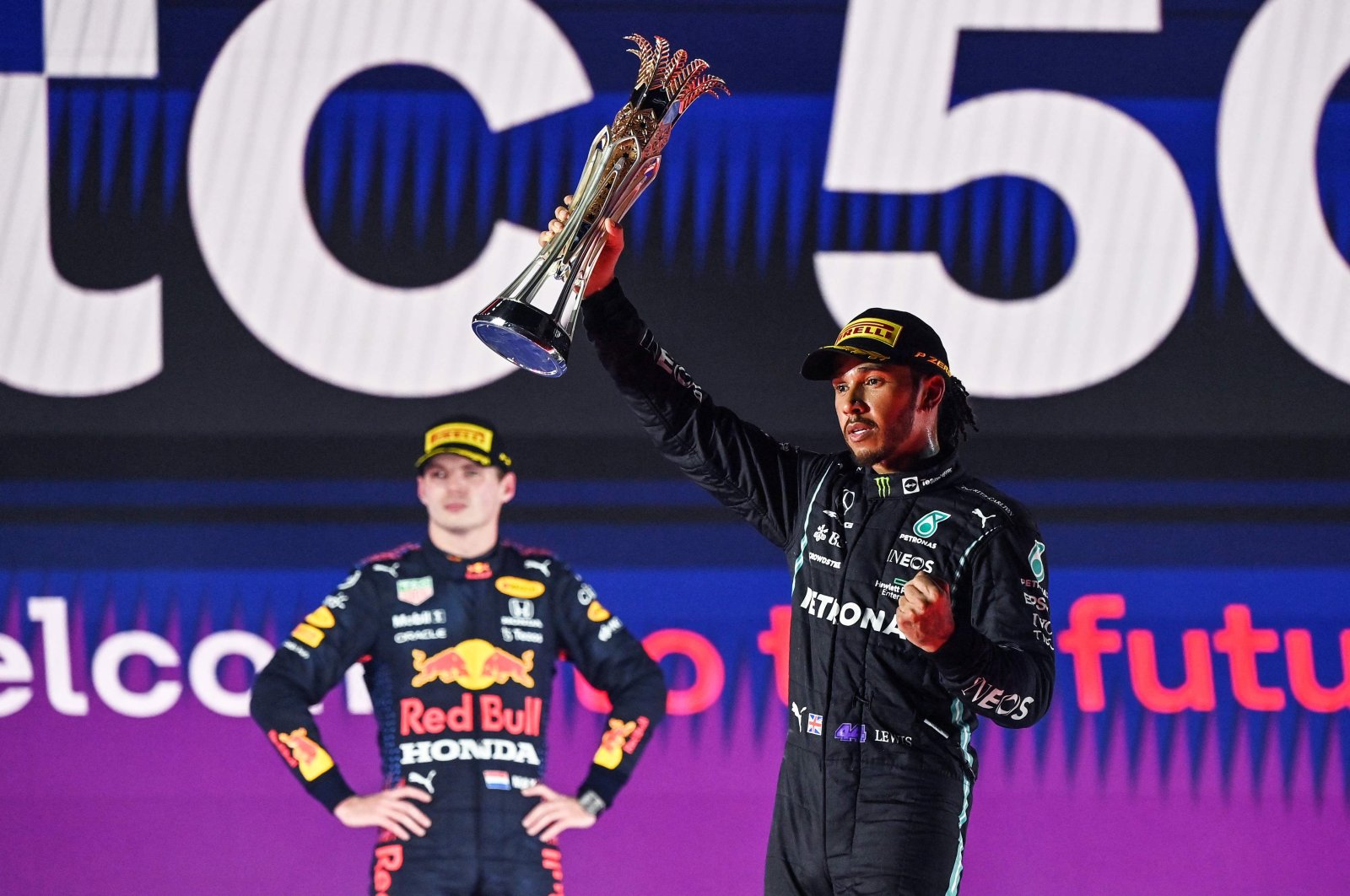 Lewis Hamilton (R) reacts with his trophy flanked by second-placed Red Max Verstappen (L), in Jeddah, Saudi Arabia, Dec. 5, 2021. (AFP PHOTO) 