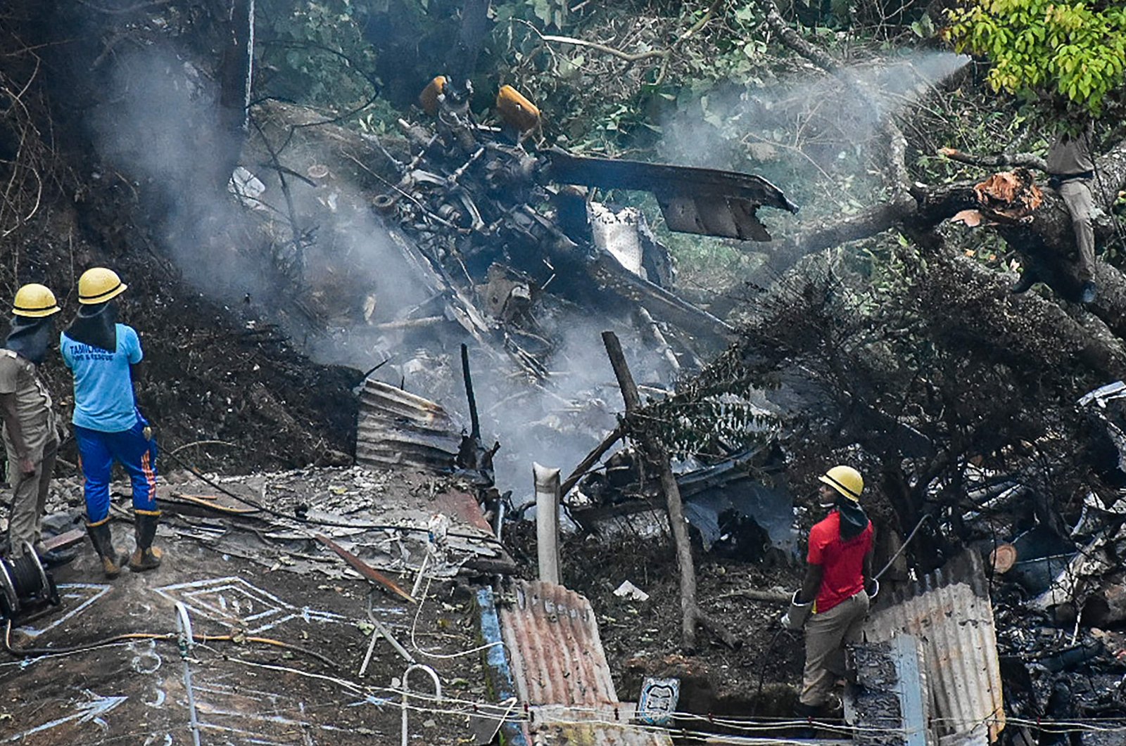 Firemen and rescue workers stand next to the debris of an IAF Mi-17V5 helicopter crash site in Coonoor, Tamil Nadu, India, Dec. 8, 2021. (AFP Photo)
