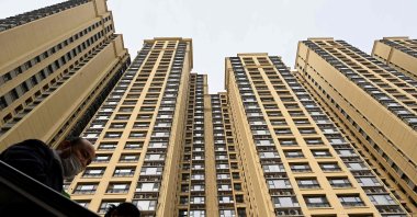 People use an escalator in front of a housing complex built by the Chinese property developer Evergrande in Beijing, China, Dec. 8, 2021. (Photo by AFP)