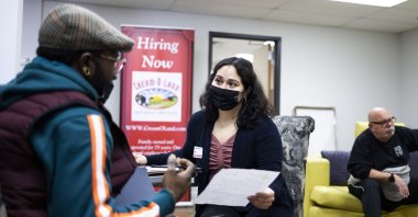Jeannie Santamaria (C), a human resources coordinator for the Cream-O-Land dairy, talks with a man (L) filling out a job application during a job fair for truck drivers and warehouse workers at the company’s warehouse in Jersey City, New Jersey, U.S., Dec. 3, 2021. (EPA Photo)