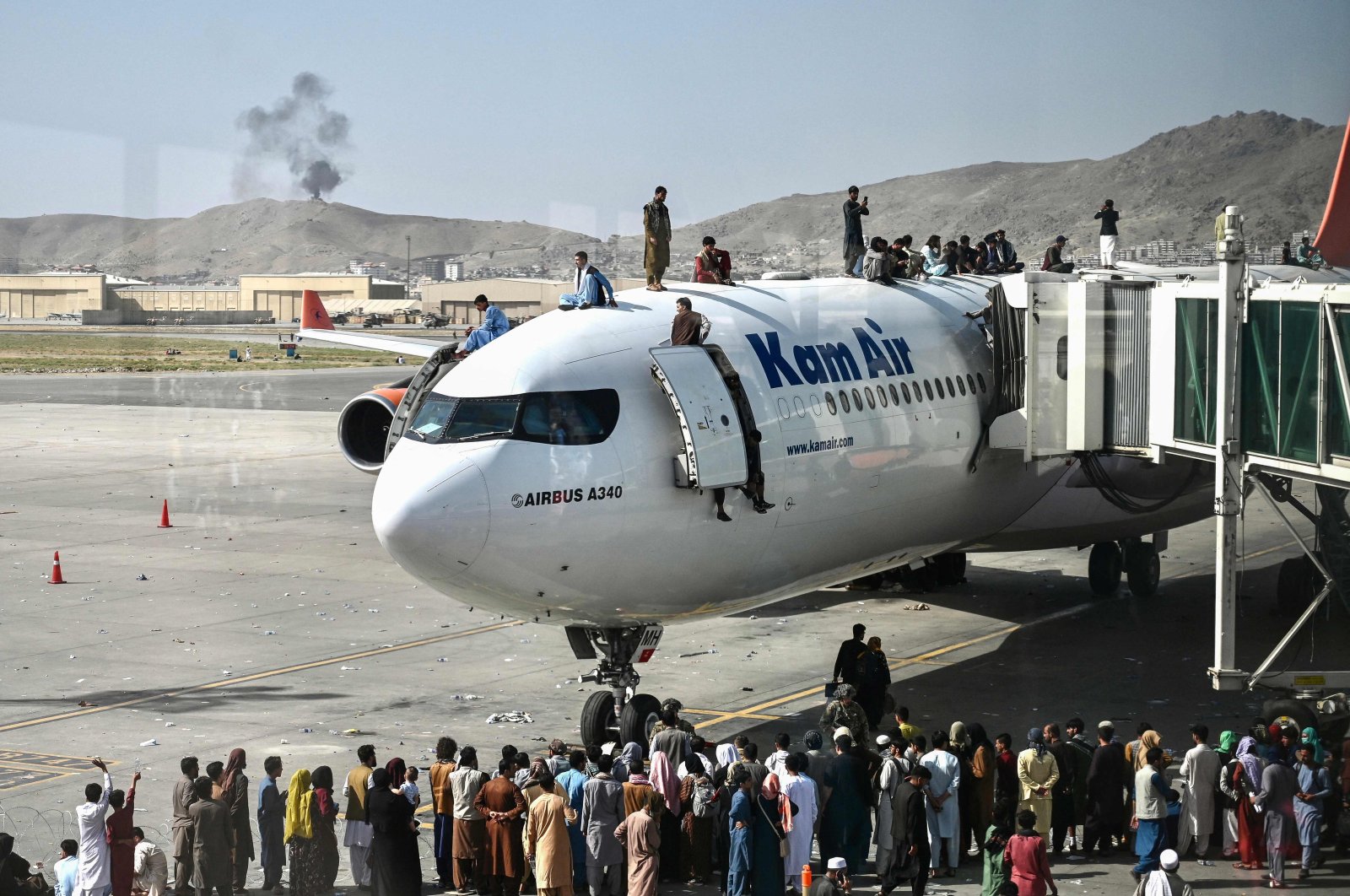 Afghan people climb atop a plane as they wait at the Kabul airport in Kabul, Afghanistan, on Aug. 16, 2021. (AFP Photo)