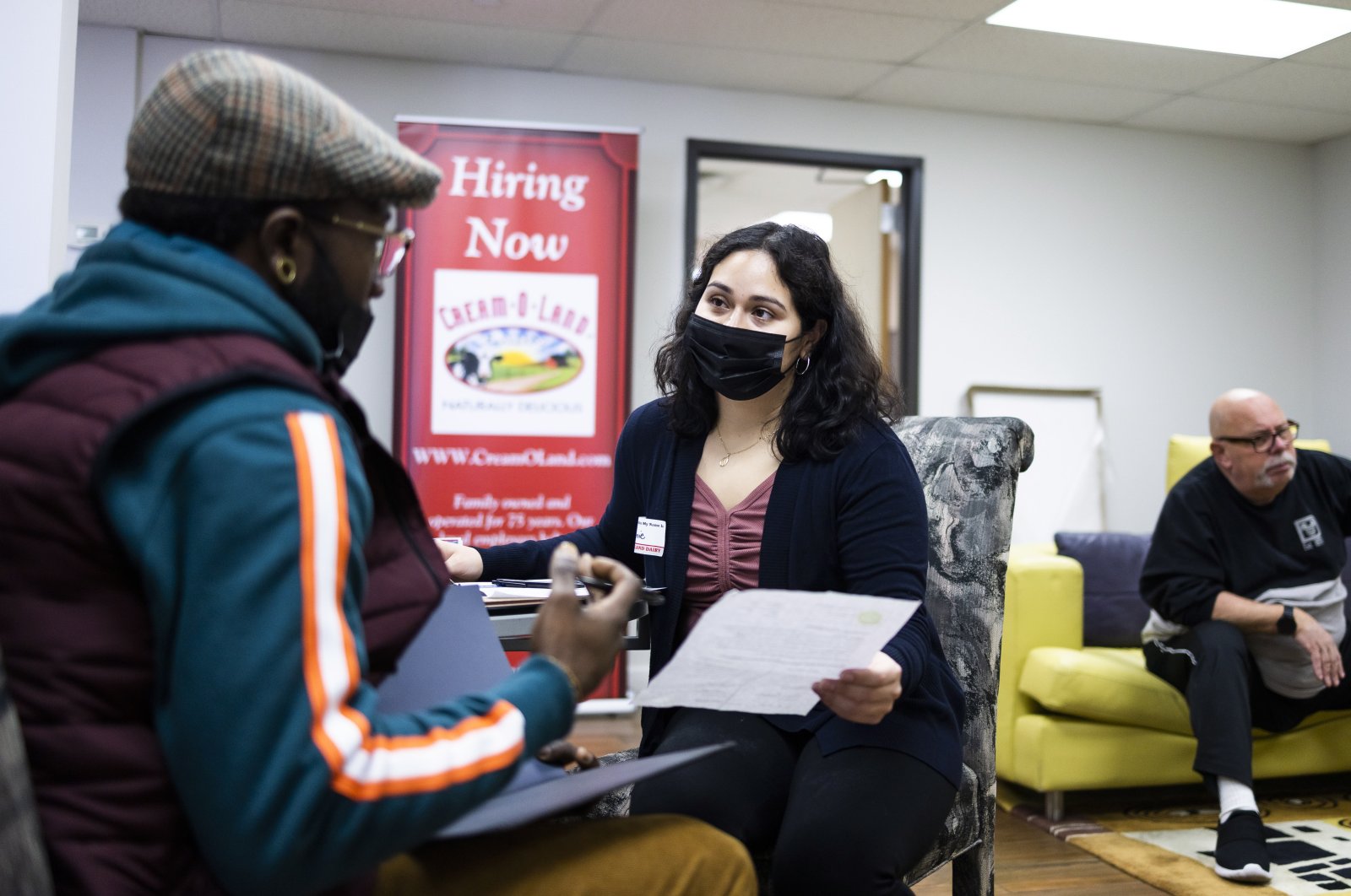Jeannie Santamaria (C), a human resources coordinator for the Cream-O-Land dairy, talks with a man (L) filling out a job application during a job fair for truck drivers and warehouse workers at the company’s warehouse in Jersey City, New Jersey, U.S., Dec. 3, 2021. (EPA Photo)