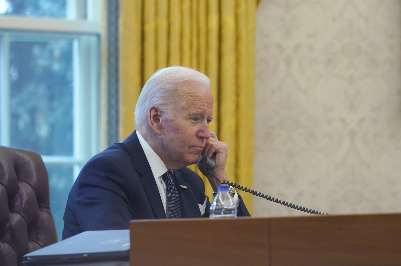 In this image made through a window, President Joe Biden talks on the phone with Ukrainian President Volodymyr Zelenskyy from the Oval Office of the White House in Washington, U.S., Dec. 9, 2021. (AP Photo)
