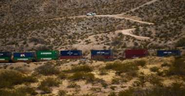 A U.S. Border Patrol vehicle sits on a hillside as a freight train carries cargo containers in the El Paso Sector along the US-Mexico border between New Mexico and Chihuahua state in Sunland Park, New Mexico, on Dec. 9, 2021 (AFP Photo)