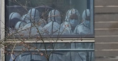 Members of a World Health Organization team are seen through a window wearing protective gear during a field visit to the Hubei Animal Disease Control and Prevention Center for another day of field visit in Wuhan in central China&#039;s Hubei province, Feb. 2, 2021. (AP Photo)