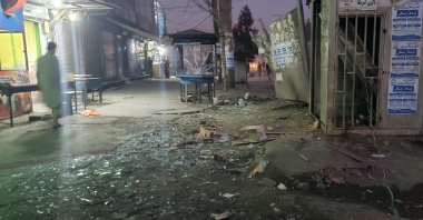 An Afghan man walks past shattered glass near the explosion site in Dasht-e-Barchi district in Kabul, Afghanistan,Dec. 10, 2021. (Photo by AFP)