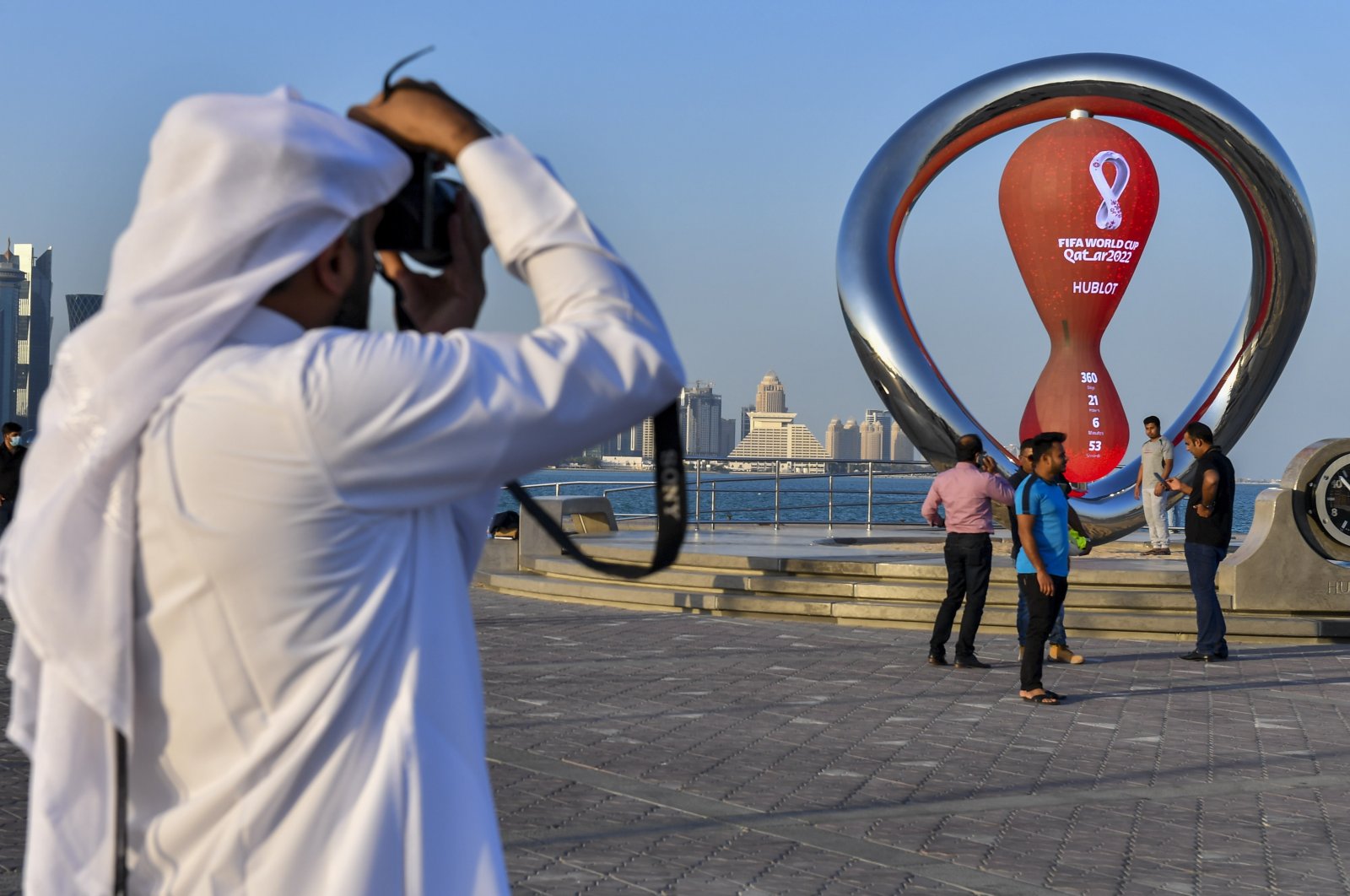 A Qatari man takes photographs of the clock counting down to the first match of the FIFA World Cup 2022 at Doha Corniche in Doha, Qatar, 25 November 2021. (EPA Photo)