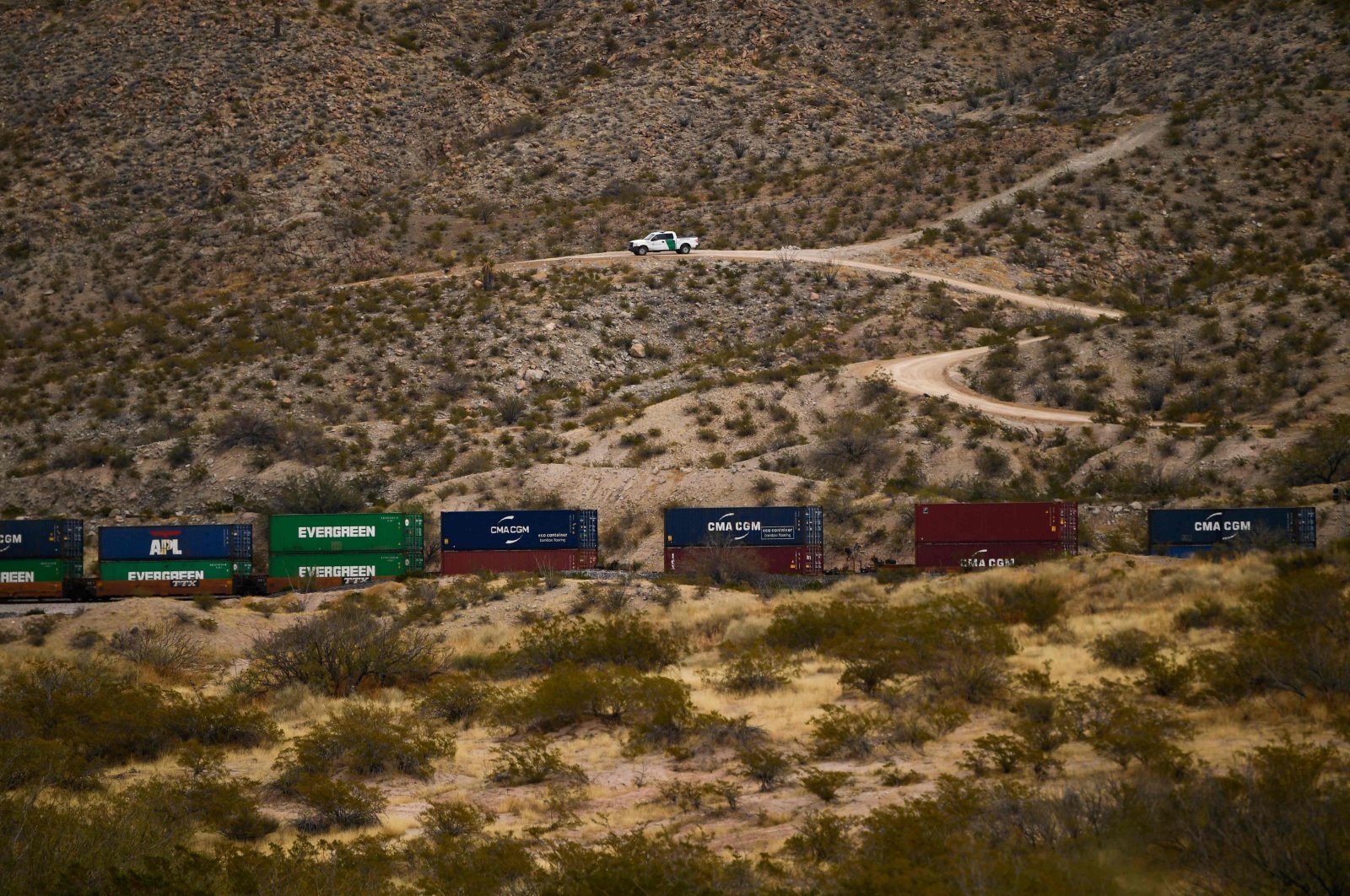 A U.S. Border Patrol vehicle sits on a hillside as a freight train carries cargo containers in the El Paso Sector along the US-Mexico border between New Mexico and Chihuahua state in Sunland Park, New Mexico, on Dec. 9, 2021 (AFP Photo)