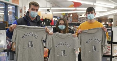 Customers inside Rough Trade hold T-shirts designed by street artist Banksy being sold to support four people facing trial accused of criminal damage in relation to the toppling of a statue of slave trader Edward Colston, Bristol, England, Dec. 11, 2021. (AP Photo)