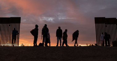 Parents-to-be from Haiti stand at a gap in the U.S.-Mexico border wall after having traveled from South America to the United States, Dec. 10, 2021 in Yuma, Arizona. (AFP Photo)