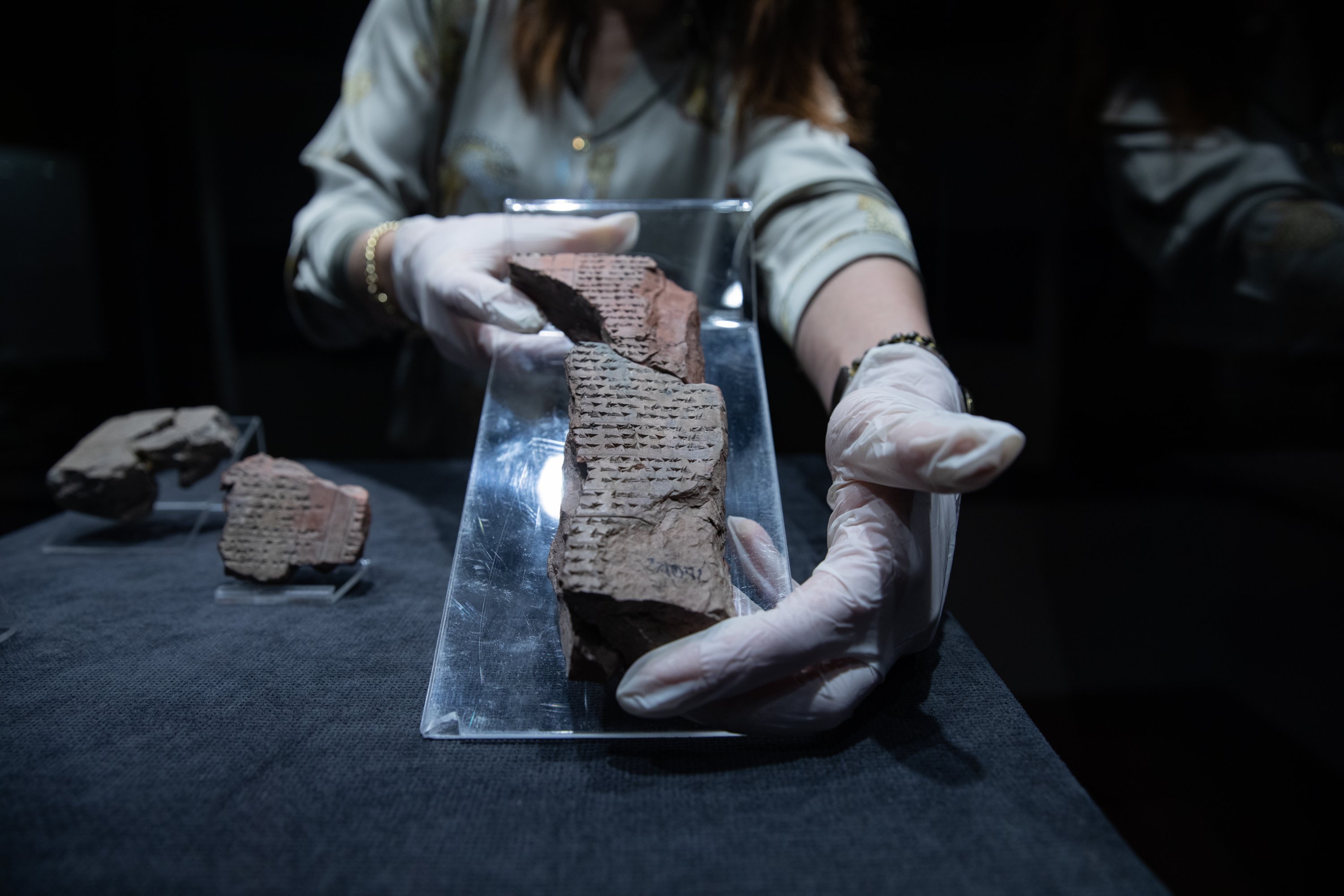 A staff member holds one of the four 3,500-year-old tablets describing several rituals are on display as part of the Izmir Archeology Museum's 'You Will See What You Can't See' project, Izmir, Turkey, Dec. 11, 2021. (AA Photo)