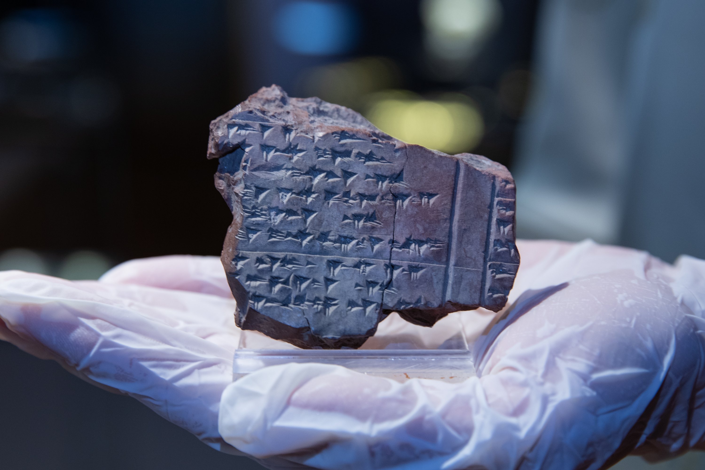 A staff member holds one of the four 3,500-year-old tablets describing several rituals are on display as part of the Izmir Archeology Museum's 'You Will See What You Can't See' project, Izmir, Turkey, Dec. 11, 2021. (AA Photo)