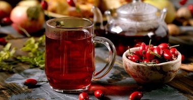 A glass of rosehip herbal tea sits near wild autumn berries and apple pie. (Shutterstock Photo)