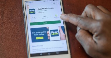 A man holds his smartphone with the display of different types of mobile loan lending service displayed on his screen, in this illustration photo taken in Nairobi, Dec. 8, 2021. (Photo by Simon MAINA / AFP)