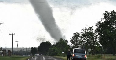 A woman looks on while a tornado rips through a residential area after touching down south of Wynnewood, Oklahoma, U.S., May 8, 2016. (Josh Edelson via AFP)