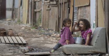 A girl eats from a pot as she eyes the camera in the Penha Brasil favela where families have started relocating during the coronavirus pandemic in Sao Paulo, Brazil, May 15, 2021. (AP File Photo)