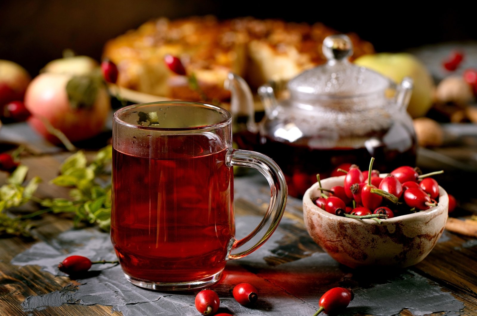 A glass of rosehip herbal tea sits near wild autumn berries and apple pie. (Shutterstock Photo)