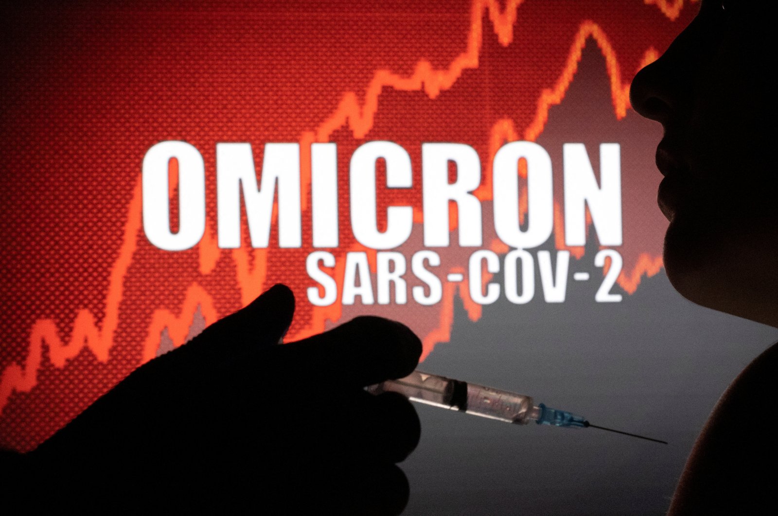 People pose with a syringe and needle in front of displayed words "OMICRON SARS-COV-2" in this illustration taken, Dec. 11, 2021. (Reuters Photo)